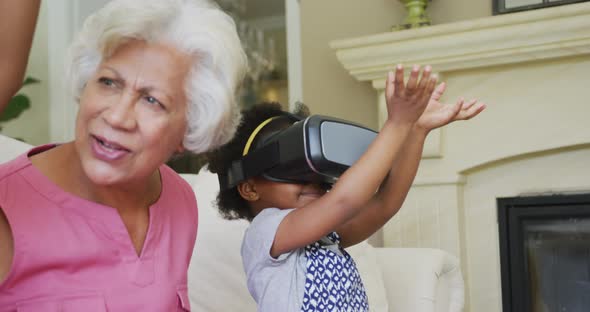 Happy african american grandmother with granddaughters using vr headset in living room