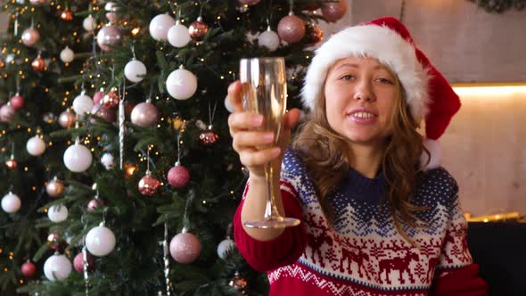 A girl dressed as Santa with a glass in her hand wishes you Merry Christmas