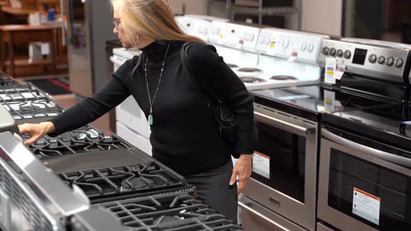 Closeup of pretty mature blonde woman looking at the features and benefits of a gas stove in a kitch