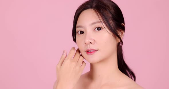 Close up Beauty shot of Beautiful Asian girl looking at camera isolated on pink background