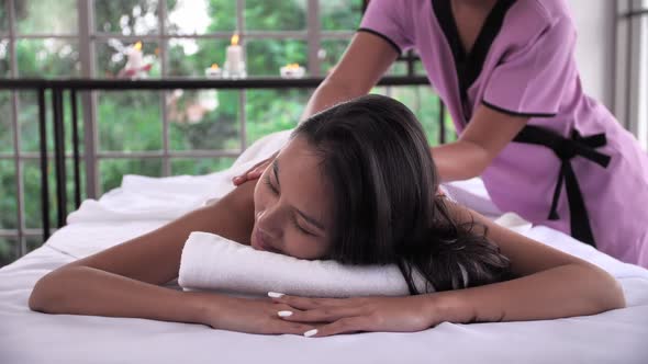 The massage therapist is massaging with essential oil on back of young Asian woman