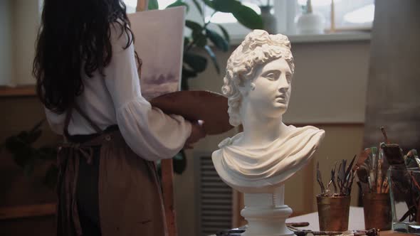 Young Woman Artist with Long Hair Drawing a Painting  Marble Bust on the Foreground
