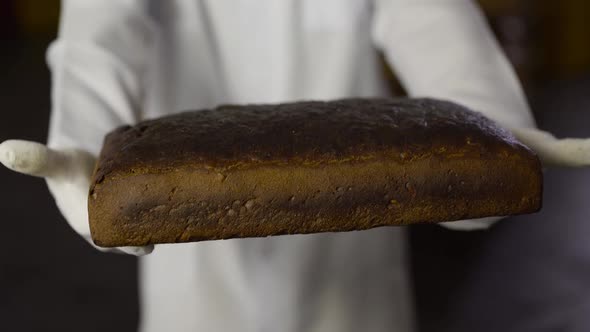 Closeup View of a Baker in Uniform Presents Freshly Baked Bread to the Camera