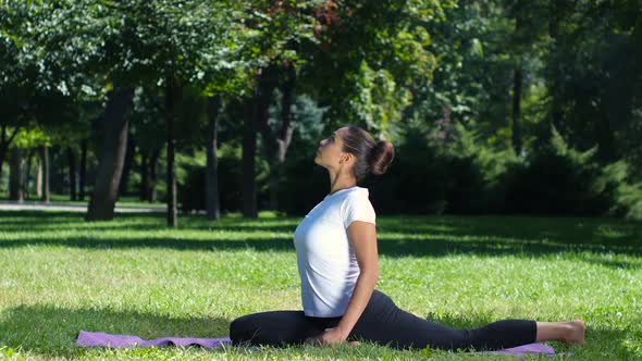 Woman Working Out Doing a Stretch Exercise in the Park on a Yoga Mat