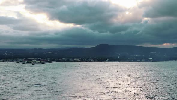 Time lapse view departing Kingston, Jamaica at sunset on a cloudy summer evening. Colors of the suns