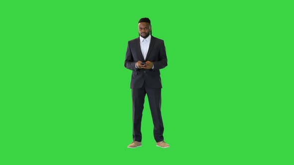 Black Man in Office Suit Typing Text on the Phone on a Green Screen Chroma Key