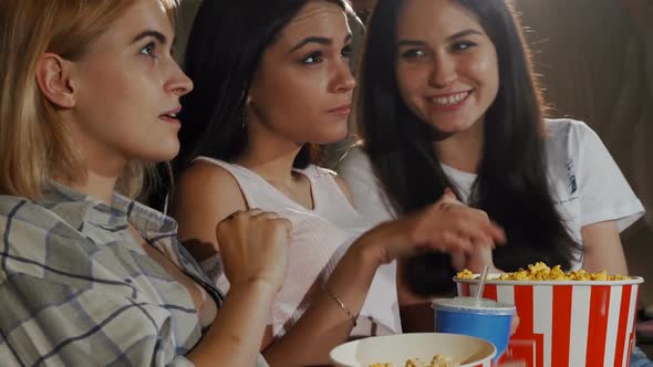 Three Young Female Friends Laughing While Watching a Movie Together