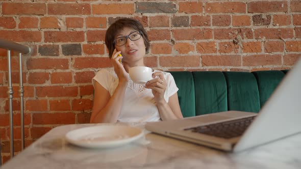 Woman Works Remotely in Cafe with Red Brick Walls