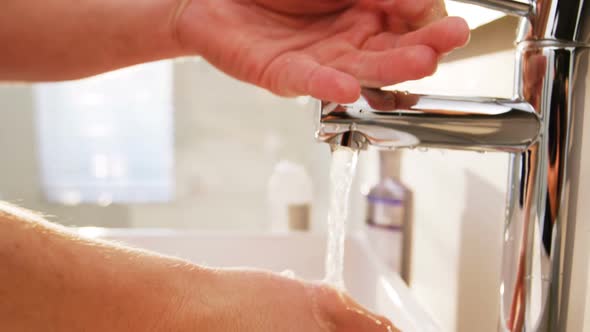 Man washing his hands in bathroom sink