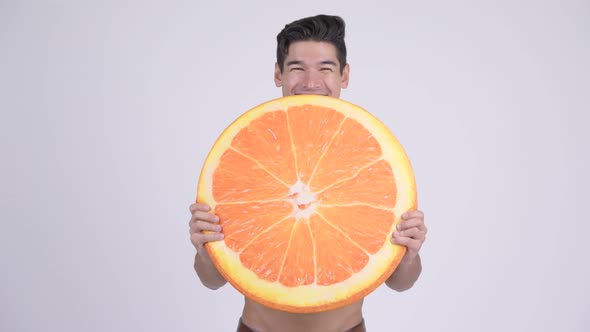 Happy Young Shirtless Muscular Man with Orange Pillow As Healthy Concept