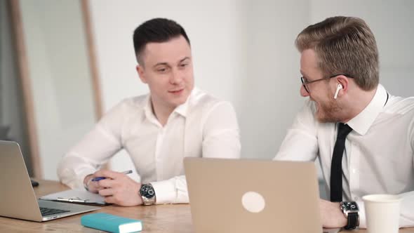 Business Partners Two Office Workers Chatting with Smile and Working at Laptops. Men Males Talking