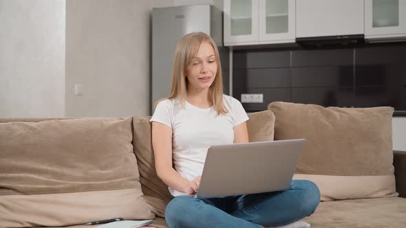 Attractive Blonde Having Video Call on Laptop at Home