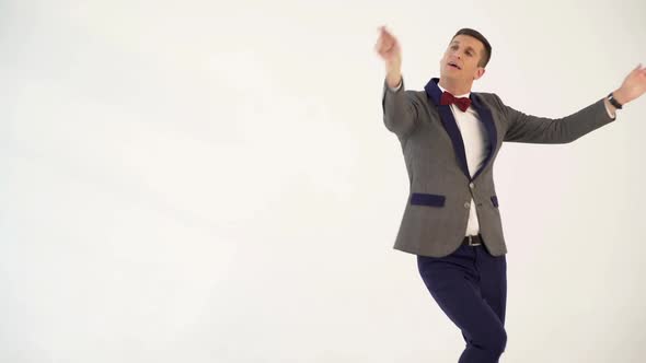 humorist in gray suit with red bow tie is dancing in the similitude of dancer with ribbon in hand