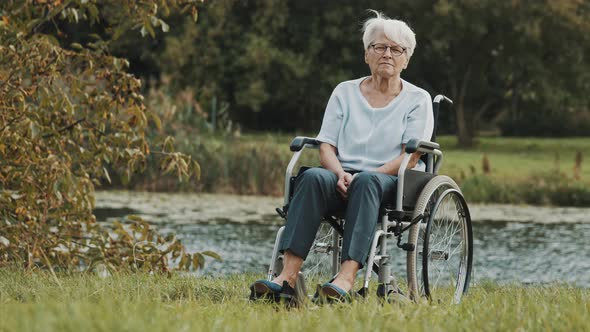 Pensive Senior Disabled Woman in the Wheelchair Near the River