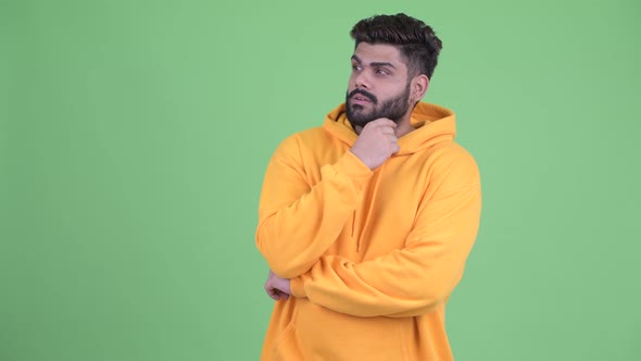 Happy Young Overweight Bearded Indian Man Thinking and Looking Up