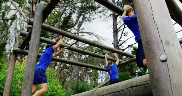 Female trainer clapping hands while fit people climbing monkey bars 4k