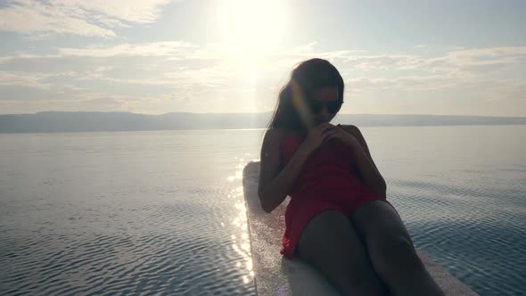 A Woman in a Red Dress Doing Crunch Exercise on the Edge of a Boat at Sunrise