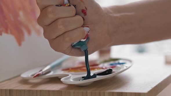 Art Student Squeezes Dark Blue Paint Into Cup on Palette