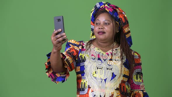 Overweight Beautiful African Woman Wearing Traditional Clothing Against Green Background