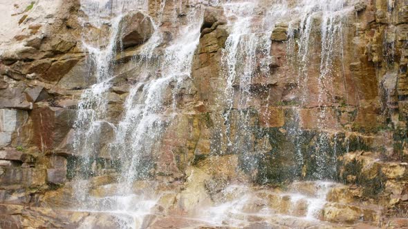 Beautiful waterfall from a cliff in the forest. video of flowing water, flowing stream among stones