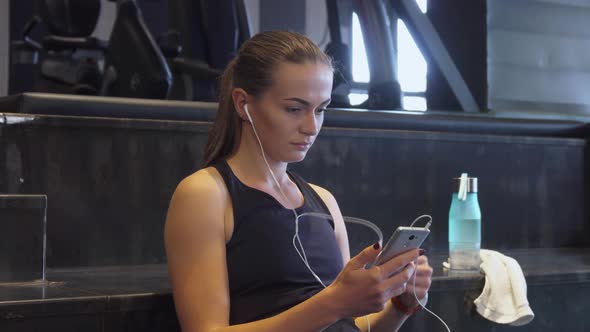 A Beautiful Girl Turns on Music in Headphones Before Doing Sports