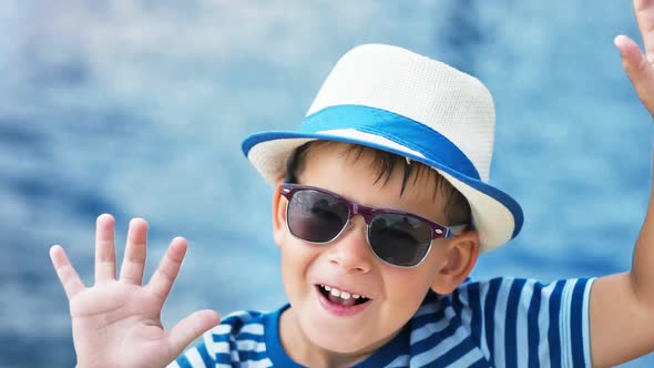 High Angle Close Up Portrait Little Boy in Sunglasses and Hat Raising Hands Having Fun Outdoor