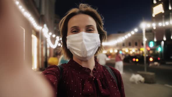 POV shot of young female tourist in medical mask outdoor making online video call looking at camera