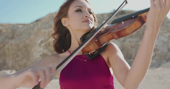 Portrait of Pretty Female Musician Playing the Violin on Nature at Cliffs