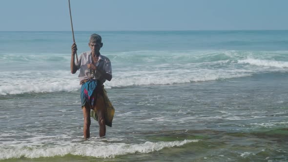 Local Man Holds Fishing Rod in Hand Against Waving Ocean