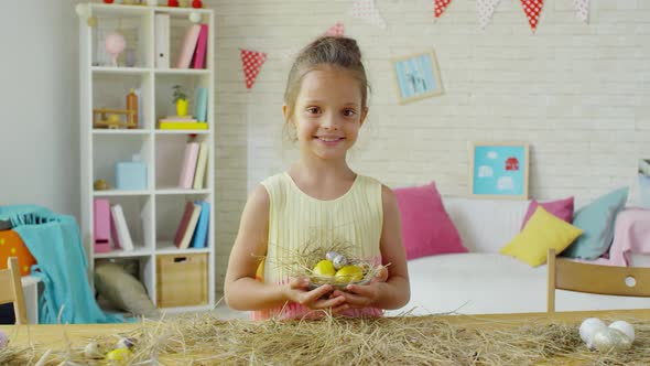 Happy Little Girl Posing with Easter Eggs in Hay Nest alt