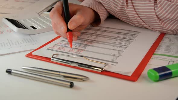 Businessman with Red Marker in Hand Examining Charts on Documents Closeup