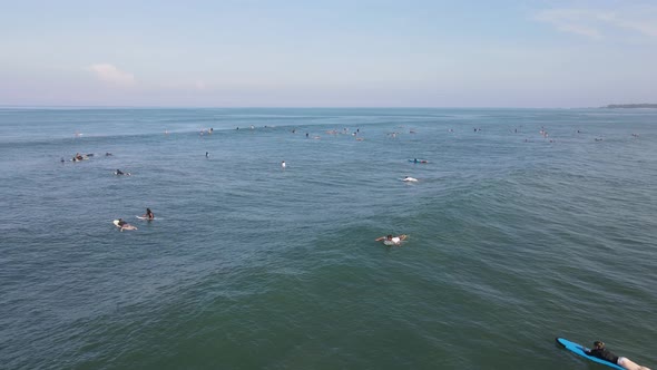 Aerial view of people surfing on waves with surfboards when vacation in Bali, Indonesia .