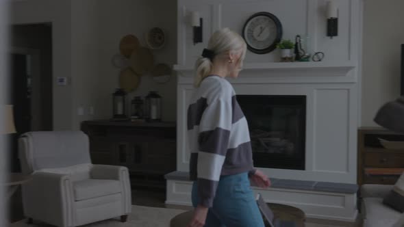 woman walking to the couch to lay down and scroll through tablet while drinking coffee in a nice hou