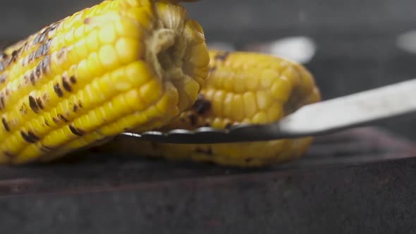 chef turns the roasted sweet corn on the grill with tongs. 