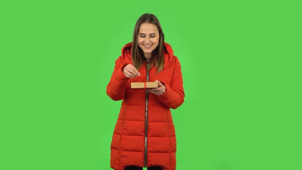 Lovely Girl in a Red Down Jacket Is Opening the Gift and Disappointed. Green Screen