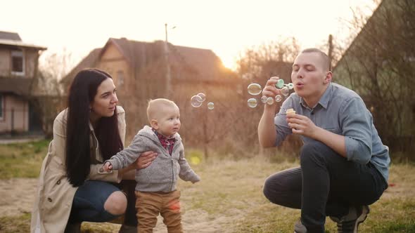 Father Blowing Soap Bubbles for His Baby Son