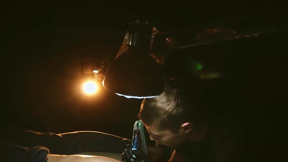 Tattoo Artist Work on Customer Leg Under Lamp Light in Dark Room