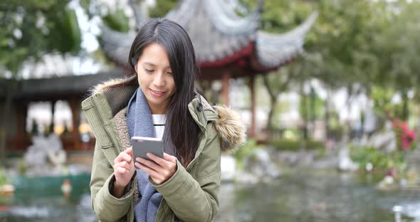 Asian Woman playing game on smart phone at china, Chinese pavilion garden