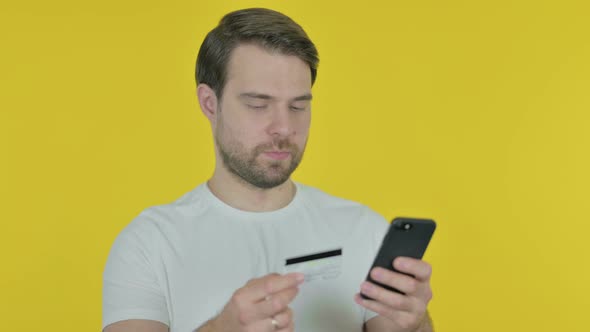 Online Shopping on Smartphone by Young Man on Yellow Background