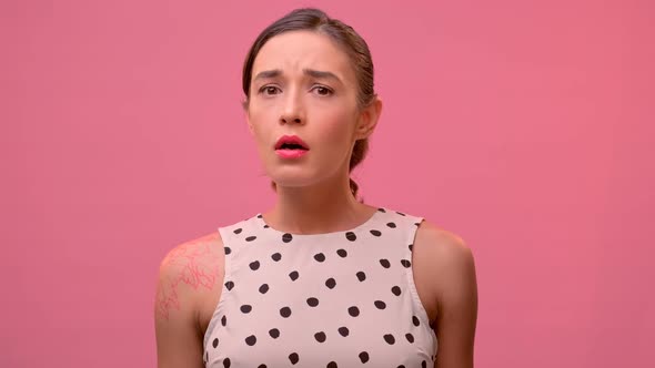 Young Millennial Woman Show Sympathy for the Interlocutor on a Pink Background.