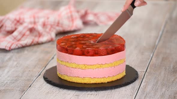 Female Hands Cutting Sweet Cake with Raspberry Mousse and Layer of Jelly.