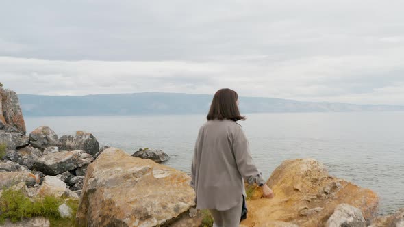 Girl is walking along a rocky shore Summer Baikal lake Olkhon island