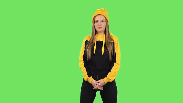 Modern Girl in Yellow Hat Is Holding Back Laughter. Green Screen