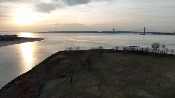 An aerial view of Calvert Vaux Park in Brooklyn, NY during a cloudy sunset. The drone camera dolly i