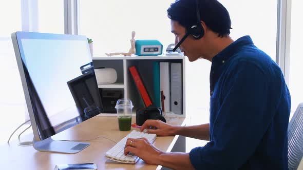 Male executive in headset working over computer at his desk 4k