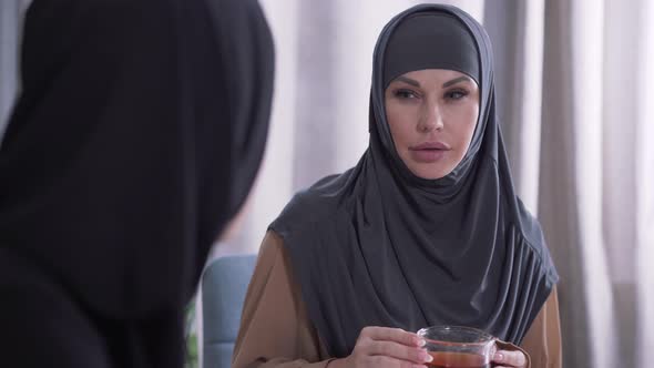 Close-up Portrait of Modern Muslim Woman on Hijab Listening To Unrecognizable Friend. Surprised