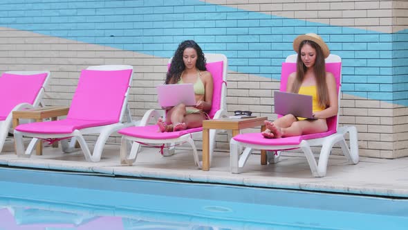 Two Millennial Girls Relax in Sun Loungers By Summer Pool