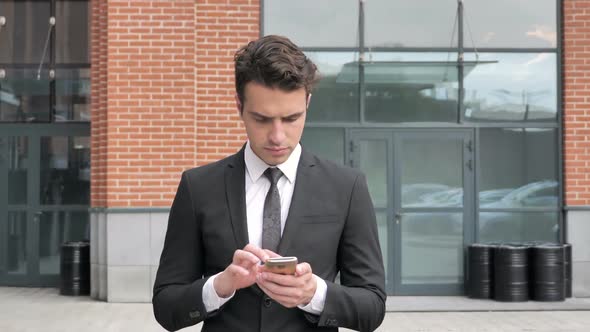 Walking Businessman Browsing Internet on Smartphone