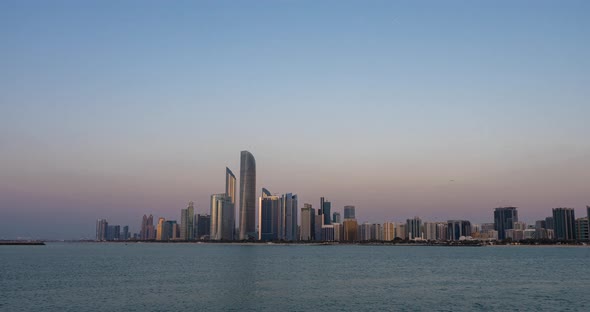 Abu Dhabi City Skyline with Skyscrapers Before Sunset with Water Reflection Day to Night Transition