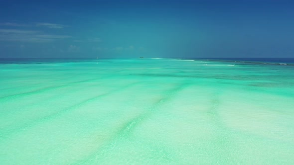 Daytime overhead travel shot of a white paradise beach and blue ocean background in colorful 4K
